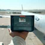 Jackery Explorer 100 Plus powerbank met op de achtergrond een vliegtuig